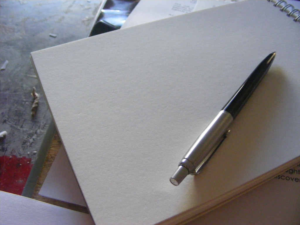 A blank spiral notebook and pen resting on a desk